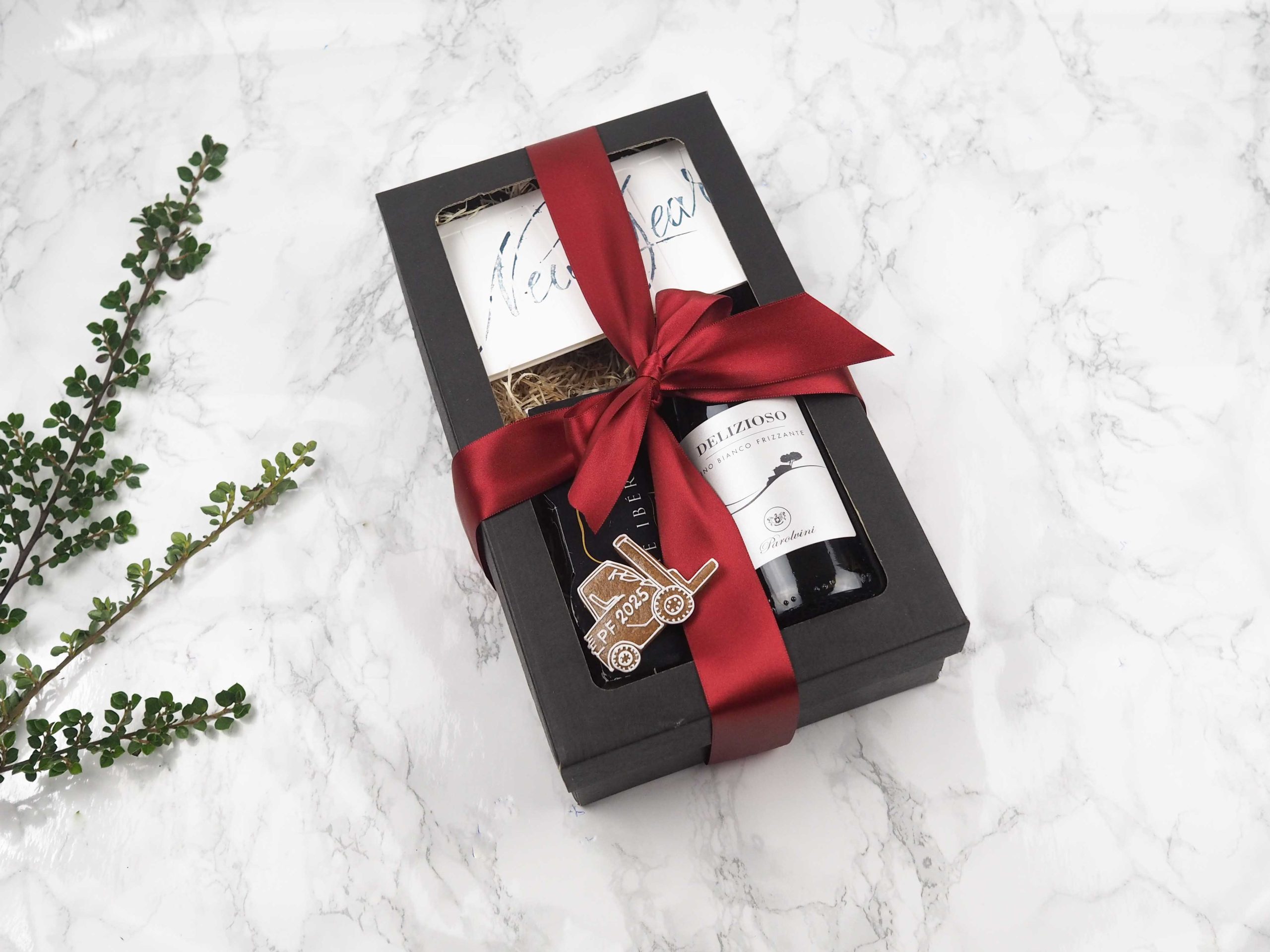 Dárkový balíček New Year v sobě obsahuje medový perníček ve tvaru vysokozdvihu, PF přání, červeného vína a vepřového paté Ibérico.